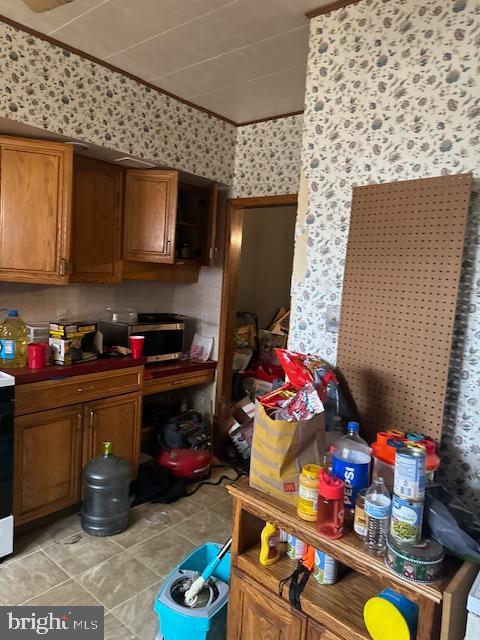 4146 Robbins Ave, Philadelphia, PA 19135 - kitchen with brown cabinetry, wallpapered walls, light tile patterned floors, dark countertops, and range