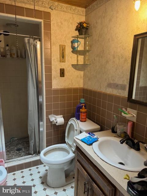 4146 Robbins Ave, Philadelphia, PA 19135 - bathroom featuring tile walls, a stall shower, vanity, toilet, and a wainscoted wall