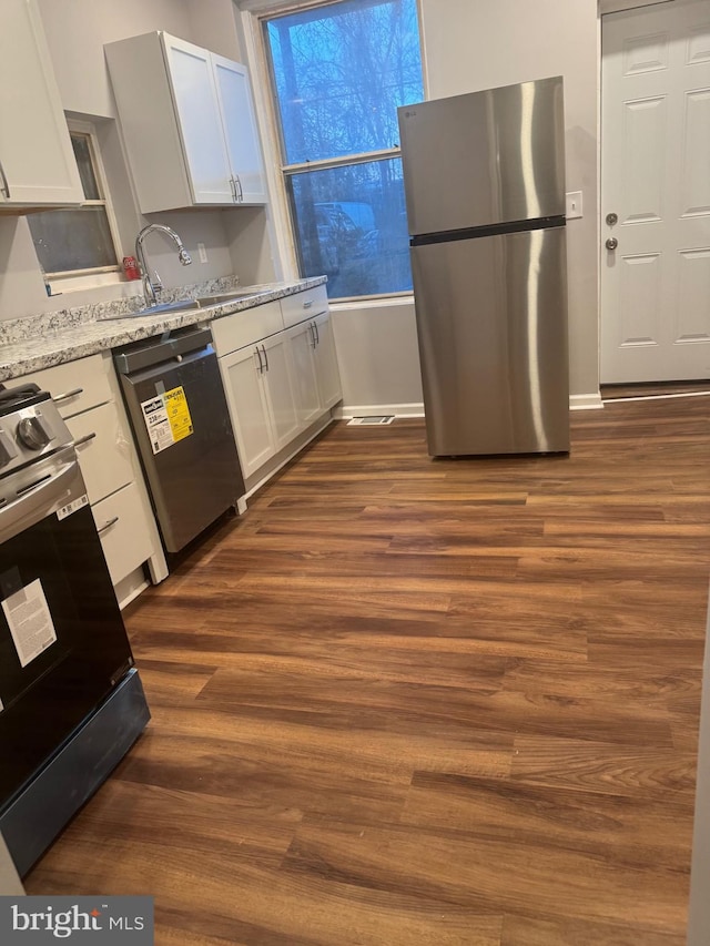 2732 Riggs Ave, Baltimore, MD 21216 - kitchen with appliances with stainless steel finishes, dark wood-style flooring, and white cabinets