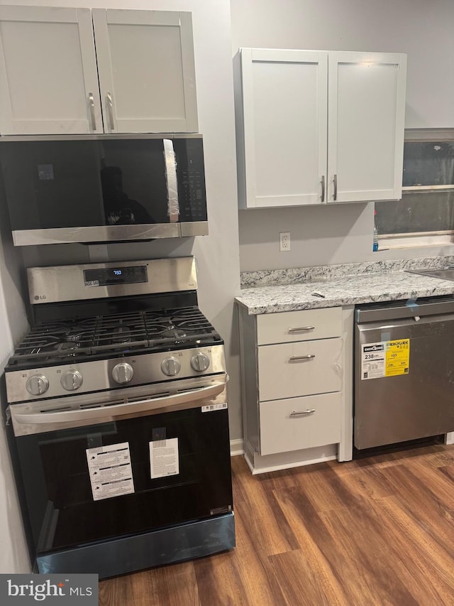 2732 Riggs Ave, Baltimore, MD 21216 - kitchen featuring stainless steel appliances, dark wood-style floors, light stone countertops, and white cabinets