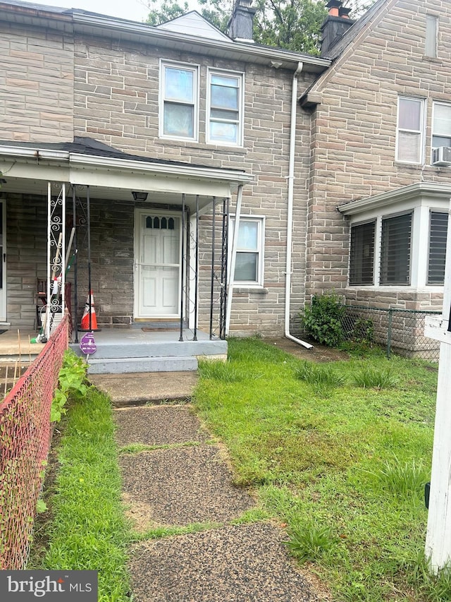 6540 Parnell Ave, Baltimore, MD 21222 - view of exterior entry featuring a chimney, a porch, a lawn, cooling unit, and stone siding