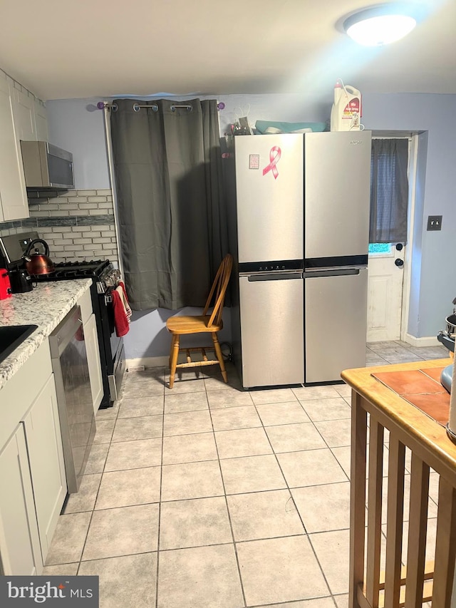 6540 Parnell Ave, Baltimore, MD 21222 - kitchen with appliances with stainless steel finishes, light tile patterned floors, white cabinets, and decorative backsplash
