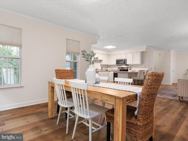 621 Admiral Dr Unit 207, Annapolis, MD 21401 - dining area featuring plenty of natural light, a textured ceiling, light wood finished floors, ornamental molding, and baseboards