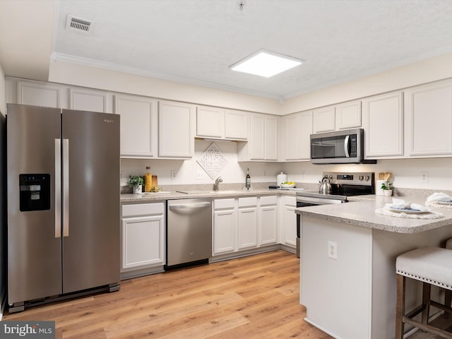 621 Admiral Dr Unit 207, Annapolis, MD 21401 - kitchen with stainless steel appliances, a peninsula, a kitchen bar, light wood-type flooring, and white cabinetry