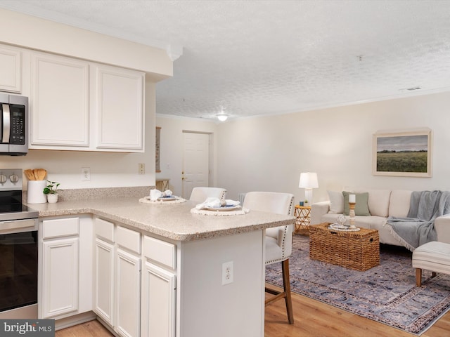 621 Admiral Dr Unit 207, Annapolis, MD 21401 - kitchen with stainless steel appliances, light wood finished floors, open floor plan, a breakfast bar area, and a textured ceiling