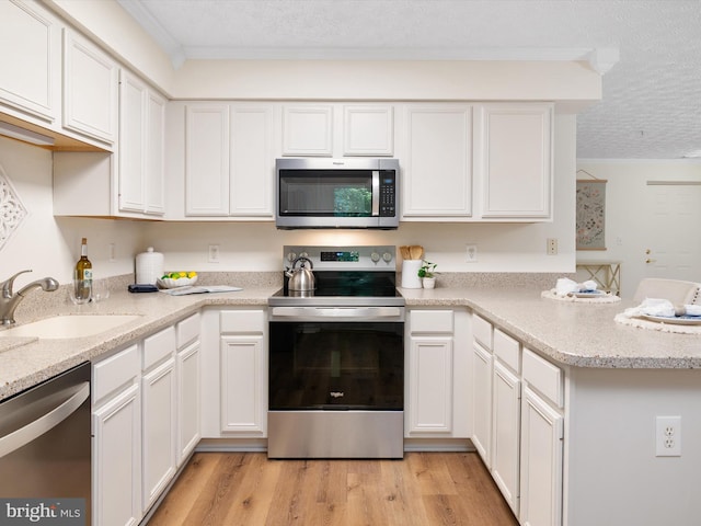 621 Admiral Dr Unit 207, Annapolis, MD 21401 - kitchen with appliances with stainless steel finishes, a textured ceiling, white cabinets, a peninsula, and light wood-style floors
