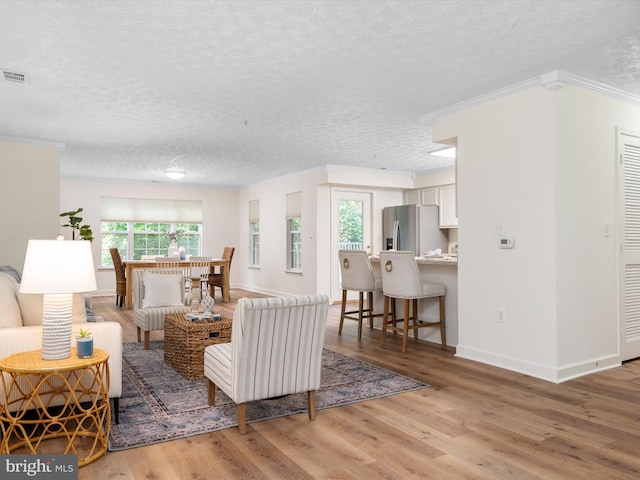 621 Admiral Dr Unit 207, Annapolis, MD 21401 - living area featuring a textured ceiling, light wood-style flooring, ornamental molding, and baseboards