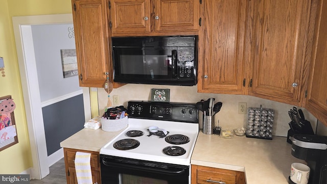 2103 W Trindle Rd, Carlisle, PA 17013 - kitchen with black microwave, range with electric cooktop, light countertops, brown cabinetry, and baseboards