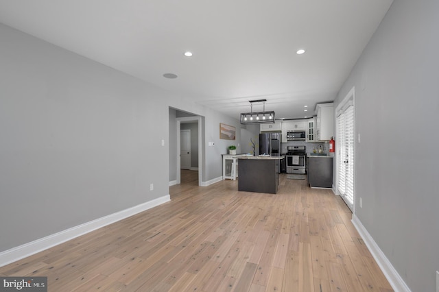 124 Washington Ave, Mount Ephraim, NJ 08059 - kitchen with stainless steel appliances, white cabinetry, a kitchen island with sink, light wood finished floors, and decorative light fixtures