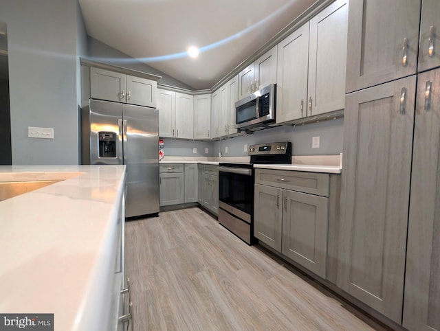87 Tulip Poplar Dr, Linden, VA 22642 - kitchen featuring stainless steel appliances, vaulted ceiling, light countertops, light wood-style flooring, and gray cabinets