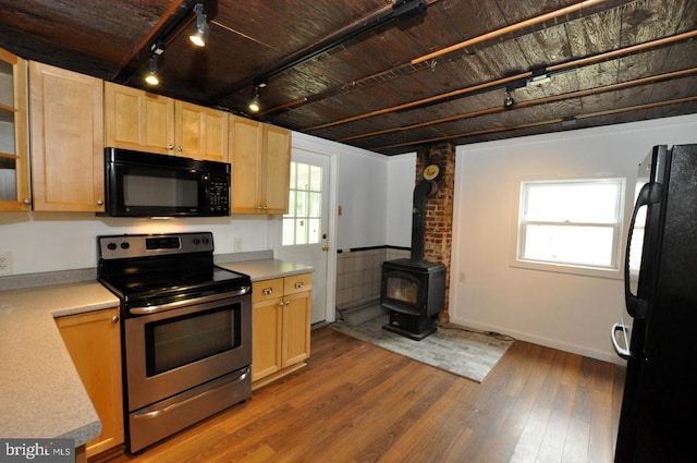 81 Jarvis St, Pemberton, NJ 08068 - kitchen featuring black appliances, light brown cabinets, dark wood-style floors, a wood stove, and light countertops