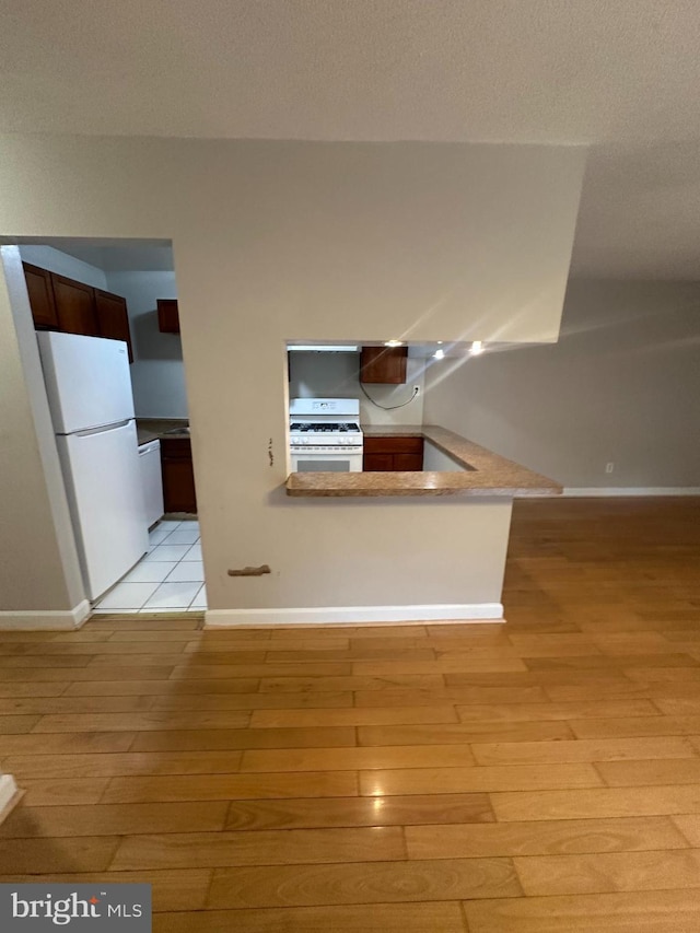 7980 Audubon Ave Unit C3, Alexandria, VA 22306 - kitchen with white appliances, light wood-style flooring, a peninsula, and baseboards