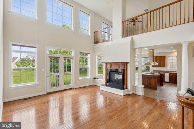 24 Tocati St, Thurmont, MD 21788 - unfurnished living room with decorative columns, a towering ceiling, light wood-style floors, a multi sided fireplace, and ceiling fan