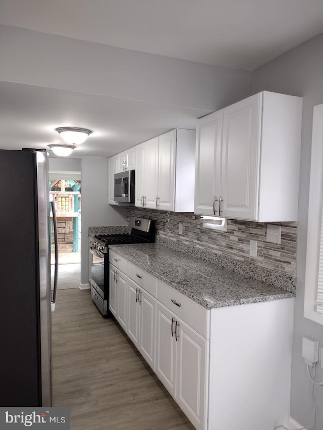 2573 Paxton St, Woodbridge, VA 22192 - kitchen with appliances with stainless steel finishes, white cabinets, decorative backsplash, and light wood-style flooring