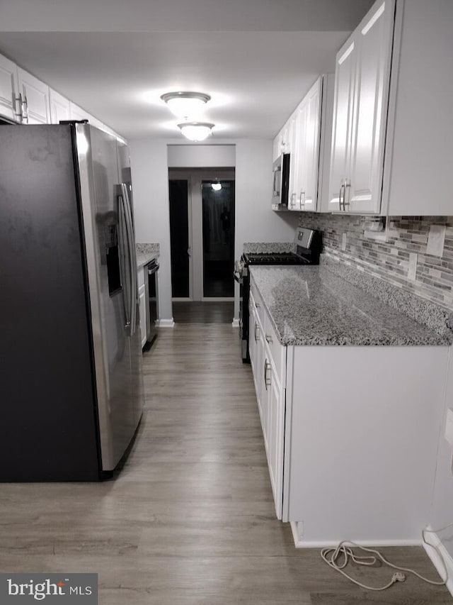 2573 Paxton St, Woodbridge, VA 22192 - kitchen with stainless steel appliances, light wood finished floors, white cabinetry, and backsplash