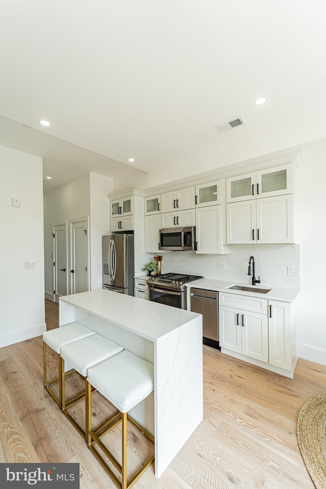 2517 Ontario Rd NW Unit Ph8, Washington, DC 20009 - kitchen with stainless steel appliances, a sink, baseboards, light wood finished floors, and a breakfast bar area