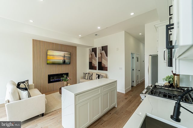 2517 Ontario Rd NW Unit Ph8, Washington, DC 20009 - kitchen featuring light wood finished floors, a glass covered fireplace, open floor plan, recessed lighting, and light countertops