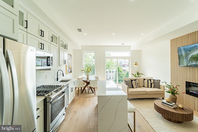 2517 Ontario Rd NW Unit Ph8, Washington, DC 20009 - kitchen with appliances with stainless steel finishes, light wood-type flooring, a sink, glass insert cabinets, and white cabinetry