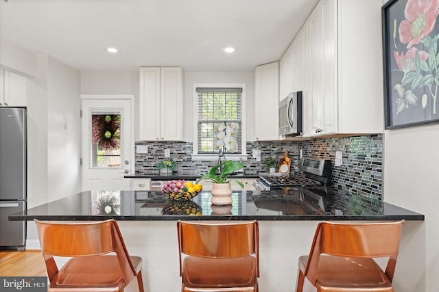 10004 Lorain Ave, Silver Spring, MD 20901 - kitchen featuring stainless steel appliances, white cabinets, decorative backsplash, dark stone countertops, and a peninsula