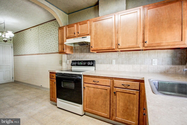 130 Main St, East Greenville, PA 18041 - kitchen with range with electric stovetop, under cabinet range hood, wallpapered walls, light countertops, and ornamental molding