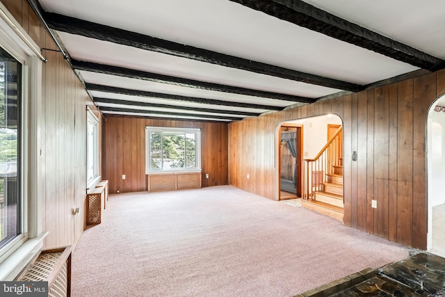 225 E State St, Coopersburg, PA 18036 - unfurnished living room featuring arched walkways, beamed ceiling, stairway, wooden walls, and carpet flooring