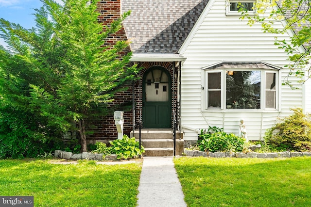 225 E State St, Coopersburg, PA 18036 - view of exterior entry featuring a shingled roof, a lawn, and a chimney