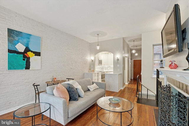 1017 Spruce St Unit C, Philadelphia, PA 19107 - living area featuring wood finished floors, brick wall, arched walkways, and baseboards