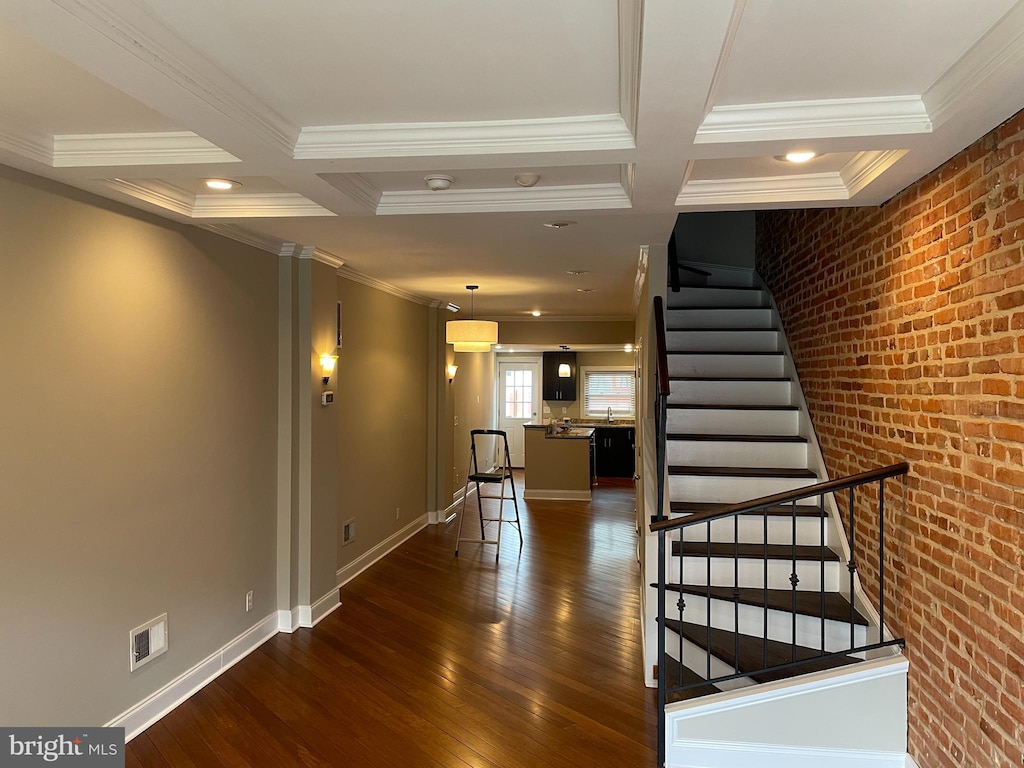 109 Curley St, Baltimore, MD 21224 - staircase featuring coffered ceiling, crown molding, hardwood / wood-style flooring, and brick wall