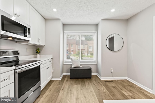 2825 Cambridge Dr, Woodbridge, VA 22192 - kitchen with appliances with stainless steel finishes, light wood-style floors, white cabinets, light countertops, and a textured ceiling