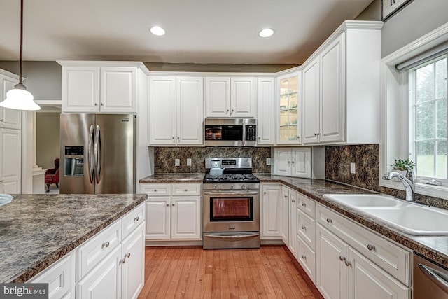 66 Light Farm Dr, Cochranville, PA 19330 - kitchen with appliances with stainless steel finishes, white cabinets, light wood-style flooring, hanging light fixtures, and backsplash