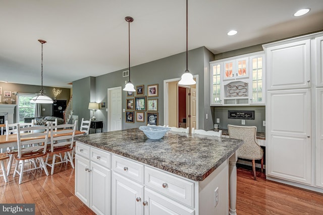 66 Light Farm Dr, Cochranville, PA 19330 - kitchen with light wood-style flooring, a kitchen island, a fireplace, white cabinets, and hanging light fixtures
