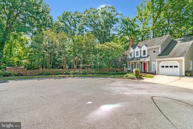 6943 Deer Run Dr, Alexandria, VA 22306 - view of front of home featuring concrete driveway, an attached garage, a chimney, and view of scattered trees