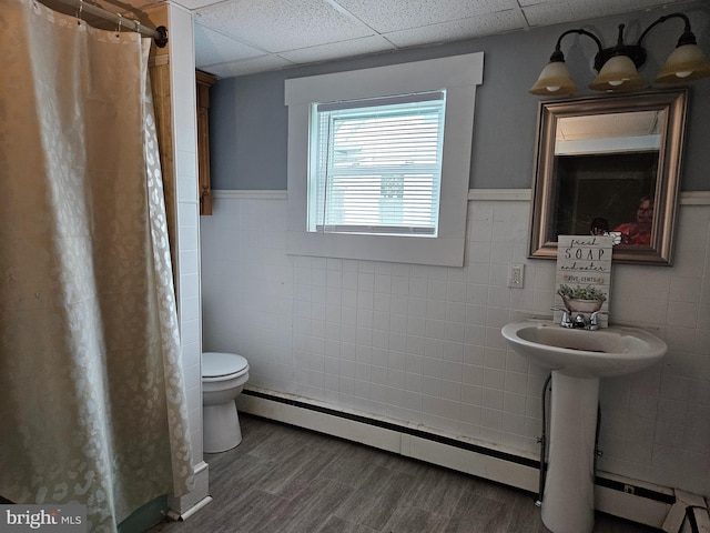 116 Maple Ave, Preston, MD 21655 - full bath featuring a baseboard heating unit, tile walls, toilet, wood finished floors, and a wainscoted wall