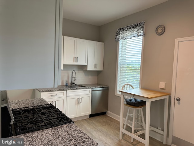 5235 Baltimore Ave, Philadelphia, PA 19143 - kitchen with stainless steel dishwasher, a sink, light wood-type flooring, backsplash, and white cabinets