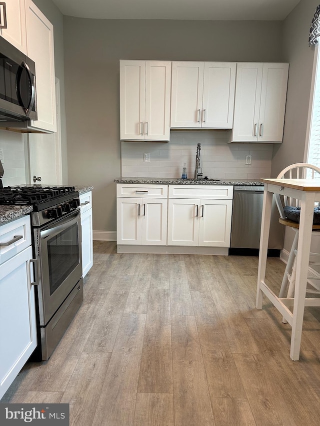 5235 Baltimore Ave, Philadelphia, PA 19143 - kitchen featuring appliances with stainless steel finishes, a sink, light wood-style floors, decorative backsplash, and white cabinets
