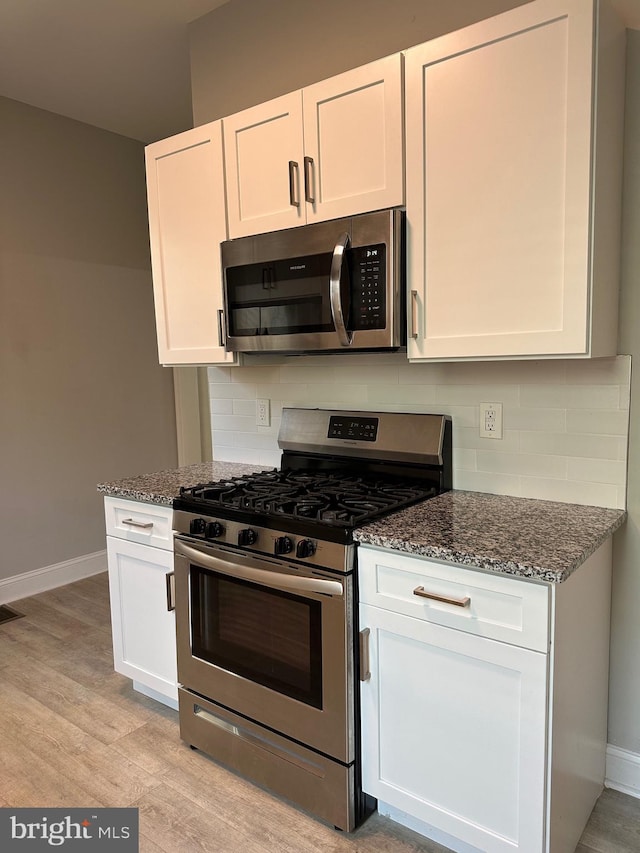 5235 Baltimore Ave, Philadelphia, PA 19143 - kitchen featuring appliances with stainless steel finishes, dark stone counters, tasteful backsplash, and white cabinetry