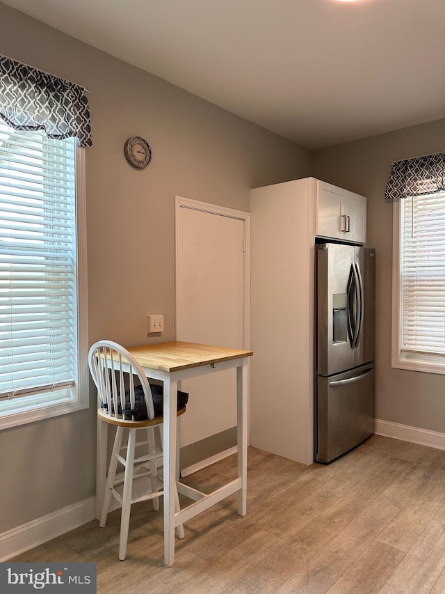 5235 Baltimore Ave, Philadelphia, PA 19143 - kitchen with stainless steel refrigerator with ice dispenser, light wood-style flooring, white cabinets, and baseboards