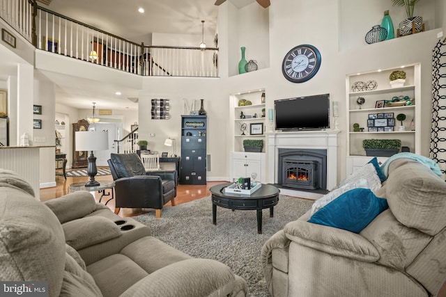 11742 Maid At Arms Ln, Berlin, MD 21811 - living room with built in shelves, a ceiling fan, a high ceiling, a glass covered fireplace, and baseboards