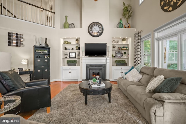 11742 Maid At Arms Ln, Berlin, MD 21811 - living area featuring built in features, healthy amount of natural light, a towering ceiling, wood finished floors, and a glass covered fireplace