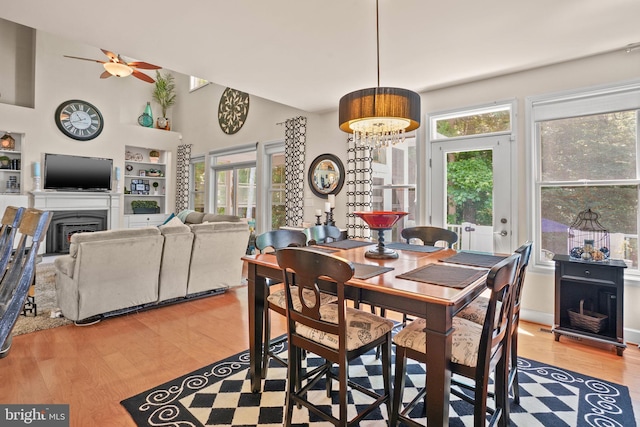 11742 Maid At Arms Ln, Berlin, MD 21811 - dining room with a fireplace, light wood-style flooring, healthy amount of natural light, ceiling fan, and a towering ceiling