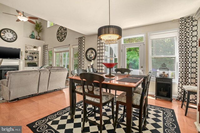 11742 Maid At Arms Ln, Berlin, MD 21811 - dining room featuring light wood-style flooring, plenty of natural light, ceiling fan, a high ceiling, and a fireplace