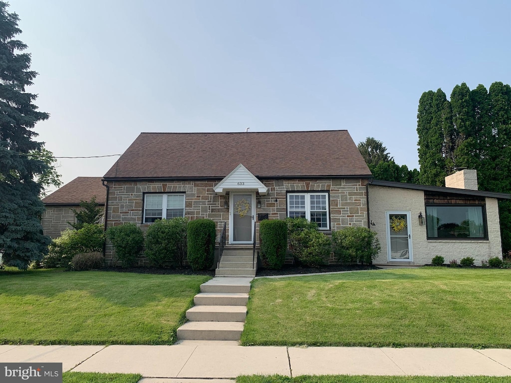 633 E Guilford St, Lebanon, PA 17046 - view of front of house with stone siding, a chimney, and a front lawn