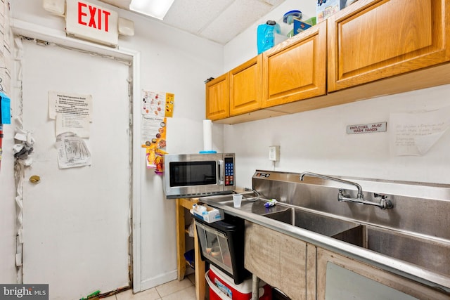 7221 W Passyunk Ave, Philadelphia, PA 19142 - kitchen with stainless steel microwave, a sink, light tile patterned flooring, and brown cabinetry
