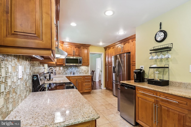8600 Fox Run, Potomac, MD 20854 - kitchen with appliances with stainless steel finishes, under cabinet range hood, light tile patterned floors, tasteful backsplash, and brown cabinetry