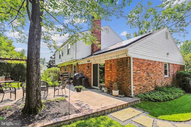 8600 Fox Run, Potomac, MD 20854 - rear view of property with a patio, a chimney, brick siding, and roof mounted solar panels