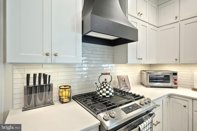 105 Fading Way, York, PA 17406 - kitchen with wall chimney range hood, gas range, decorative backsplash, light countertops, and white cabinetry