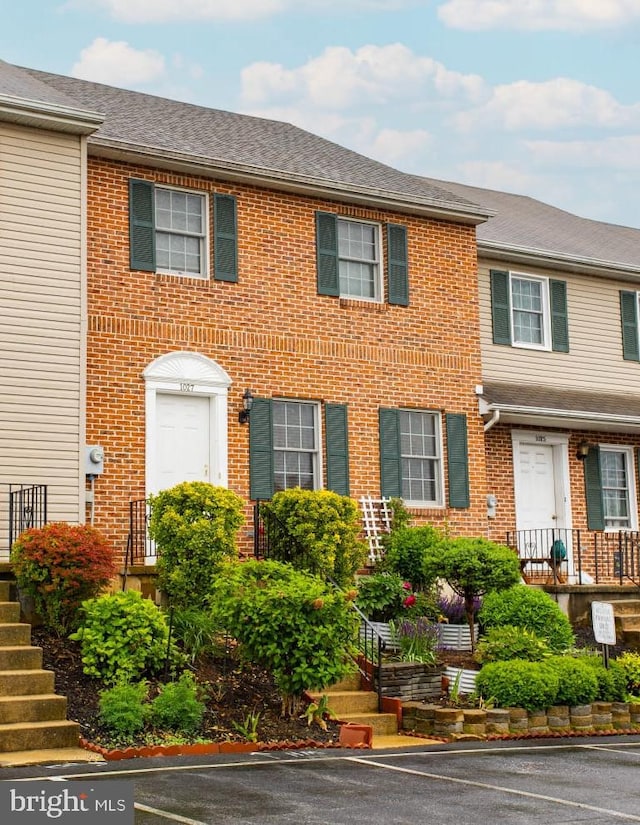 1027 Fredrick Blvd, Reading, PA 19605 - view of property featuring brick siding, uncovered parking, stairs, and roof with shingles