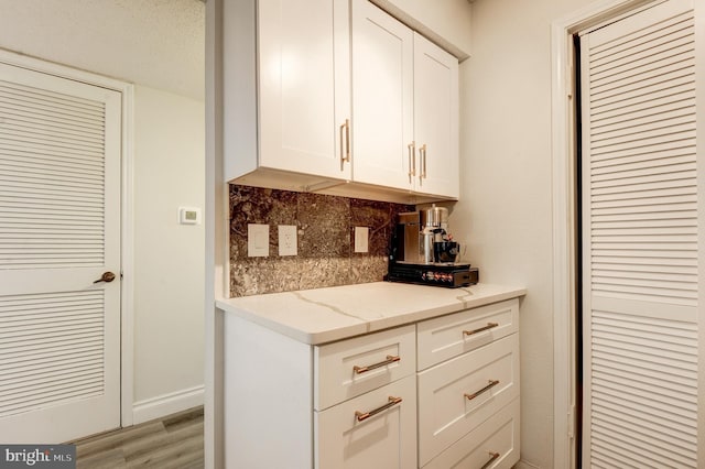 1511 Lincoln Way Unit 201B, Mclean, VA 22102 - kitchen with tasteful backsplash, white cabinetry, light stone counters, and light wood-style flooring