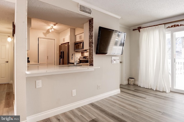 1511 Lincoln Way Unit 201B, Mclean, VA 22102 - kitchen with stainless steel appliances, a textured ceiling, a sink, wood finished floors, and light countertops