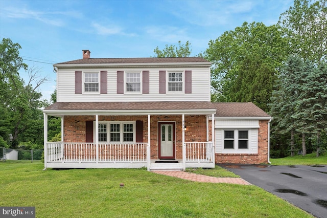 4410 Pilgrim Ln, Upper Chichester, PA 19061 - view of front of house with covered porch, a chimney, brick siding, a front lawn, and asphalt driveway